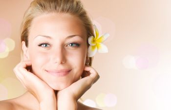 Face of a happy youngish-looking woman wearing a flower in her hair.